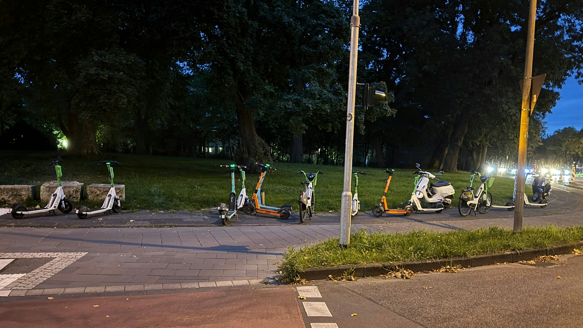 Auf einem Gehweg sind zahlreiche E-Scooter aufgereiht.