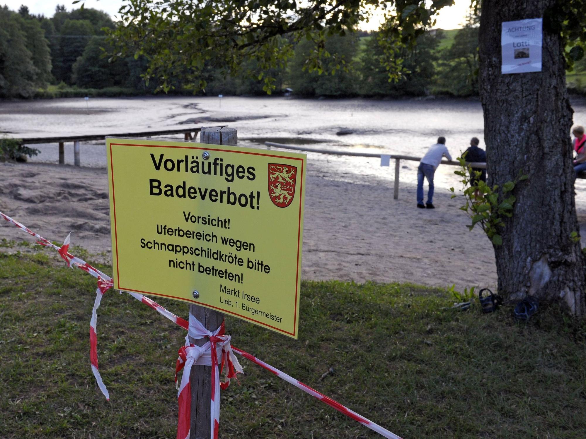 Ein Verbotsschild am Ufer eines Weihers, der für die Jagd auf eine Schildkröte leergepumpt wurde.
