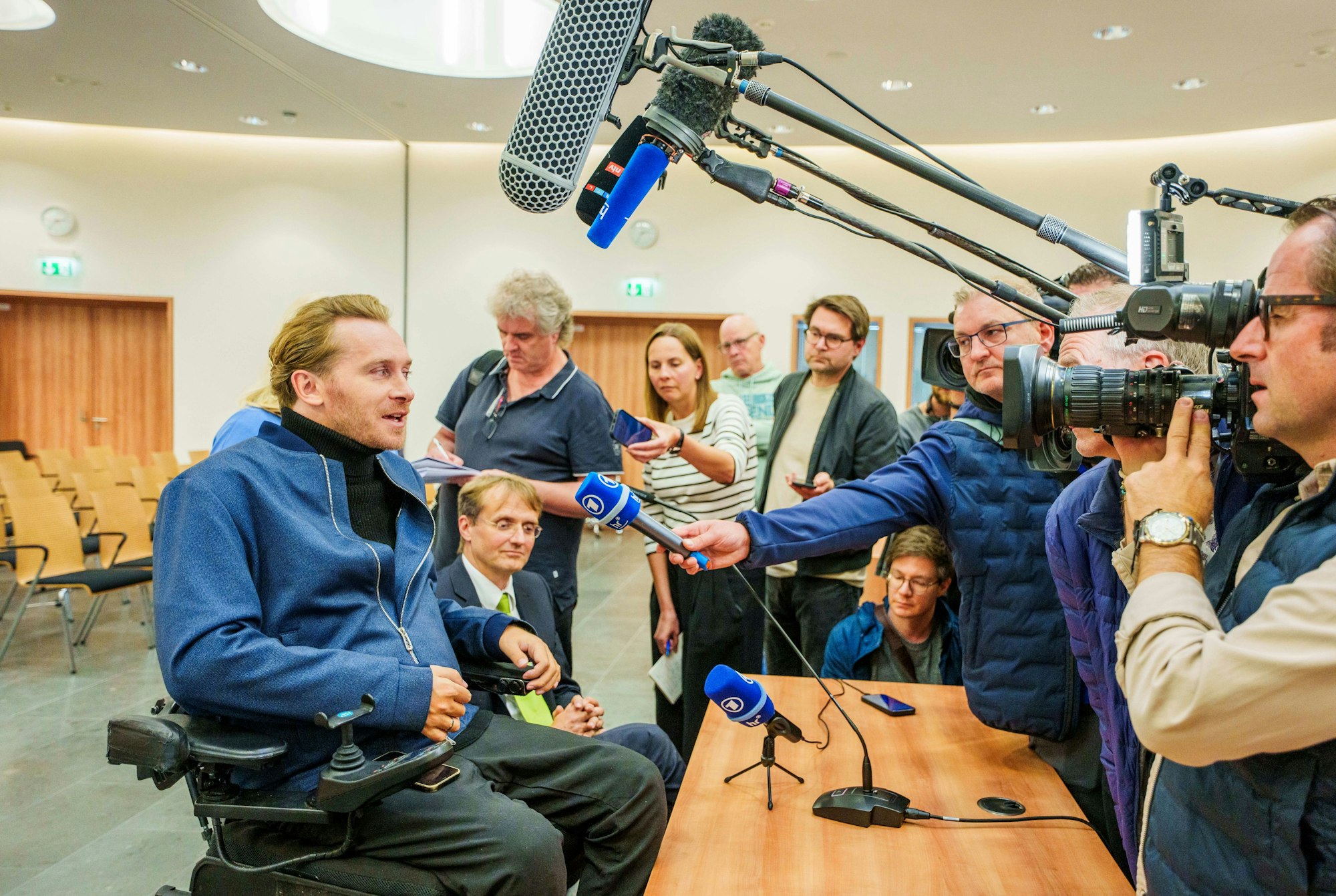 24.09.2025, Hessen, Kassel: Samuel Koch (l) äußert sich nach der Urteilsverkündung am Bundessozialgericht gegenüber den Journalisten, neben ihm sitzt sein Anwalt Oliver Negele