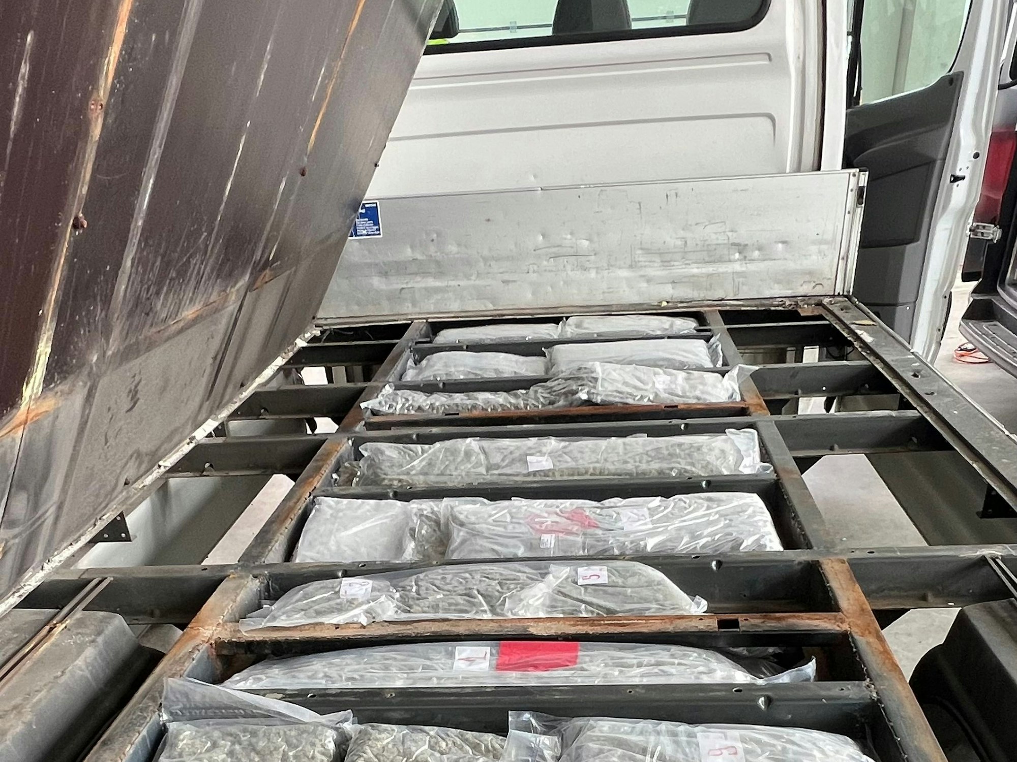 Die Ladefläche eines Transporters ist aufgeklappt, darunter liegen Tüten voll mit Drogen.