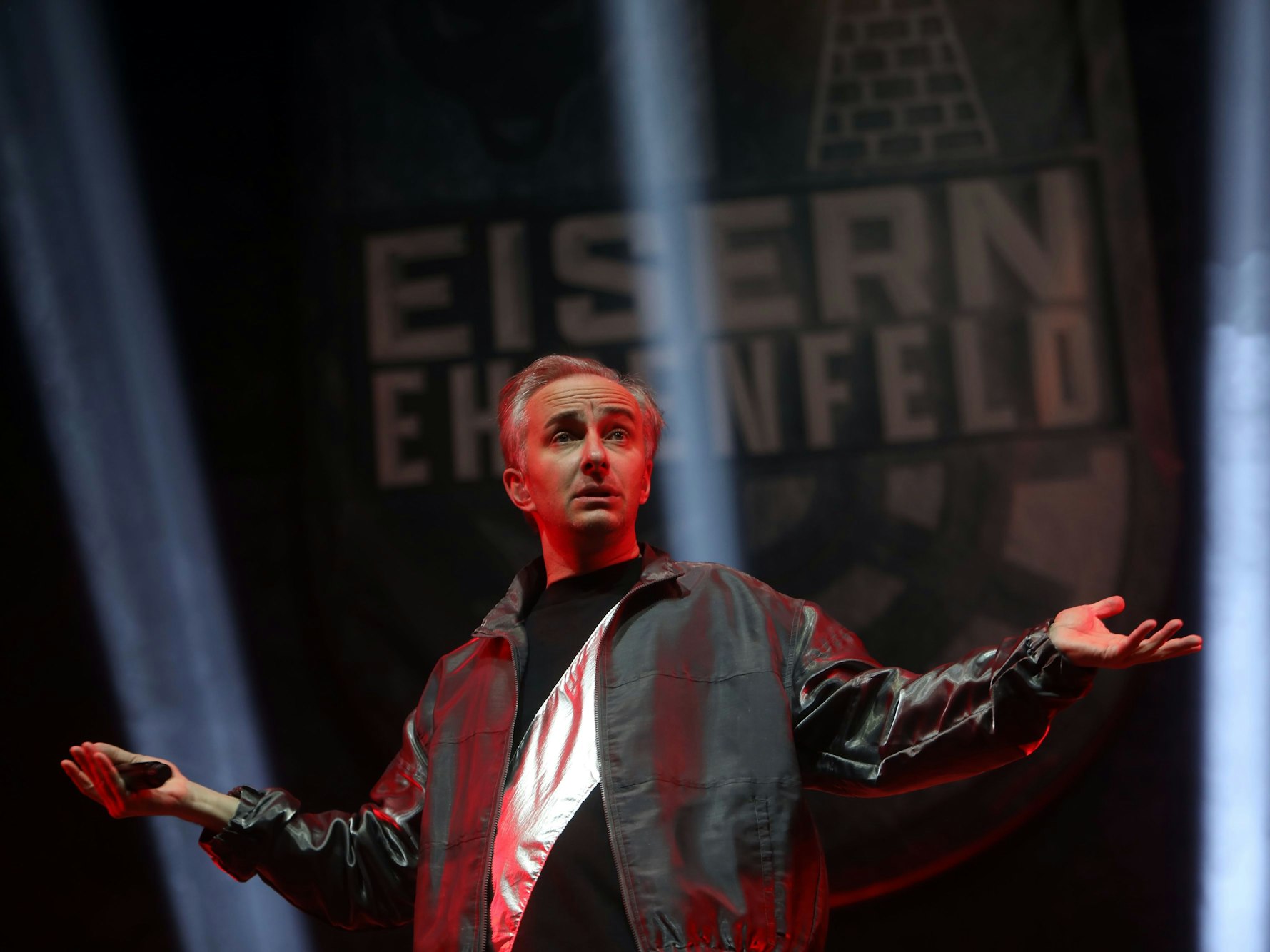 Jan Böhmermann steht mit ausgebreiteten Armen und fragendem Gesichtsausdruck auf der Bühne.