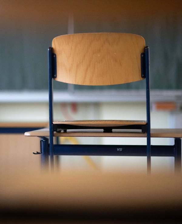 Ein Stuhl steht in einem Klassenzimmer auf einem Tisch.