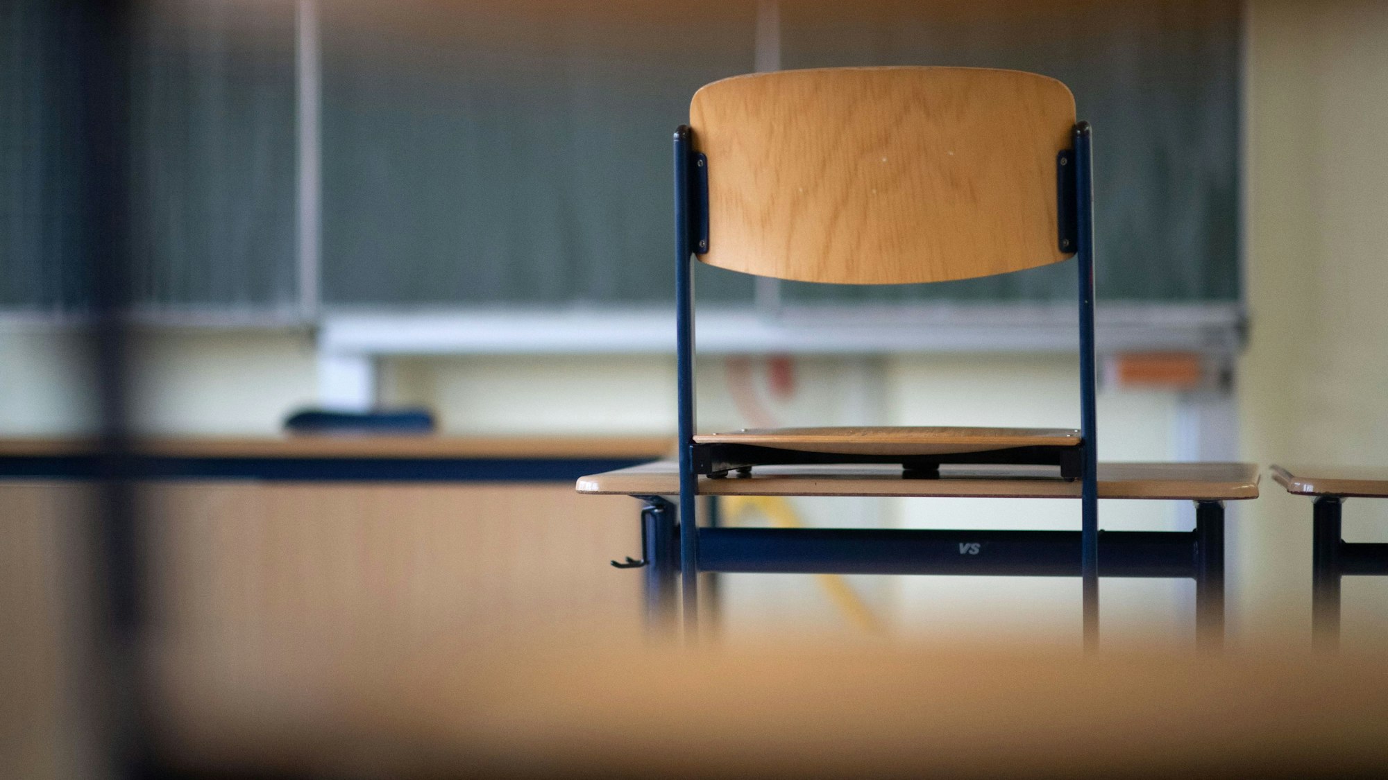 Ein Stuhl steht in einem Klassenzimmer auf einem Tisch.