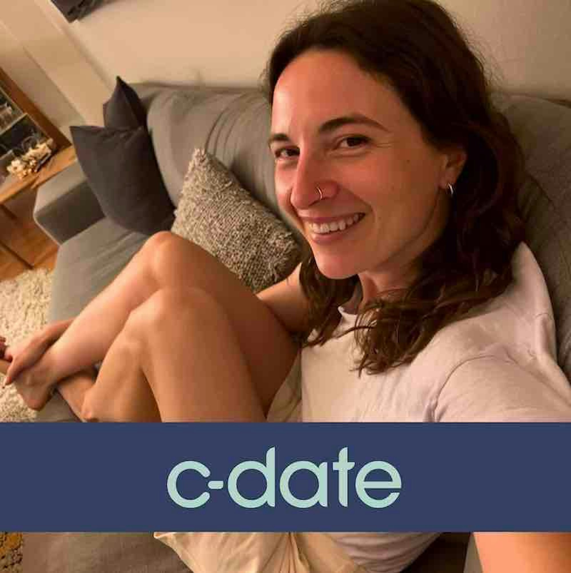 Eine junge Frau sitzt entspannt auf der Couch und schießt ein Selfie von sich.