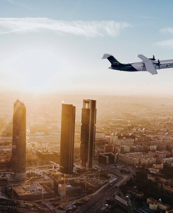 Ein Flugzeug fliegt über eine Großstadt im Abendlicht.