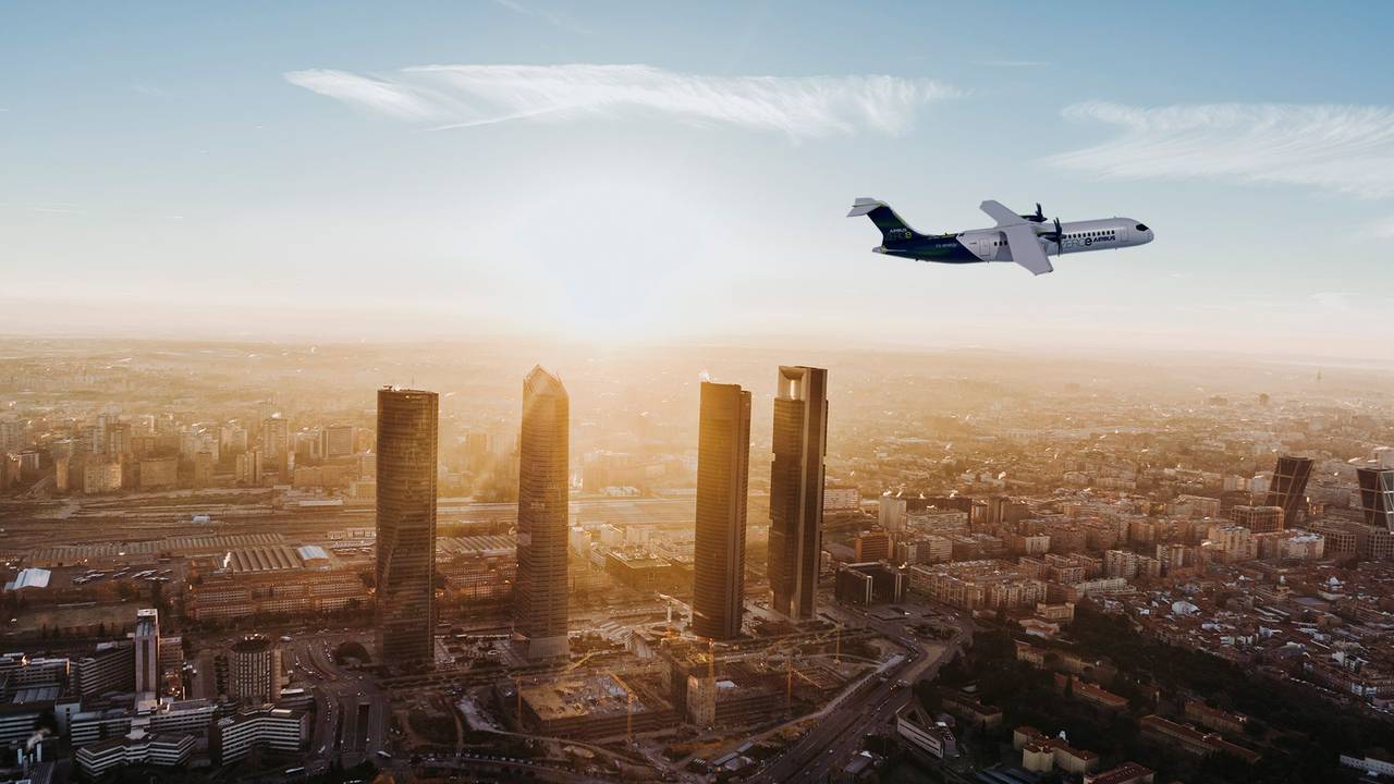 Ein Flugzeug fliegt über eine Großstadt im Abendlicht.