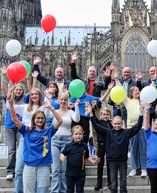 Kinder der Bürgergarde stehen mit bunten Luftballons vor dem Dom.