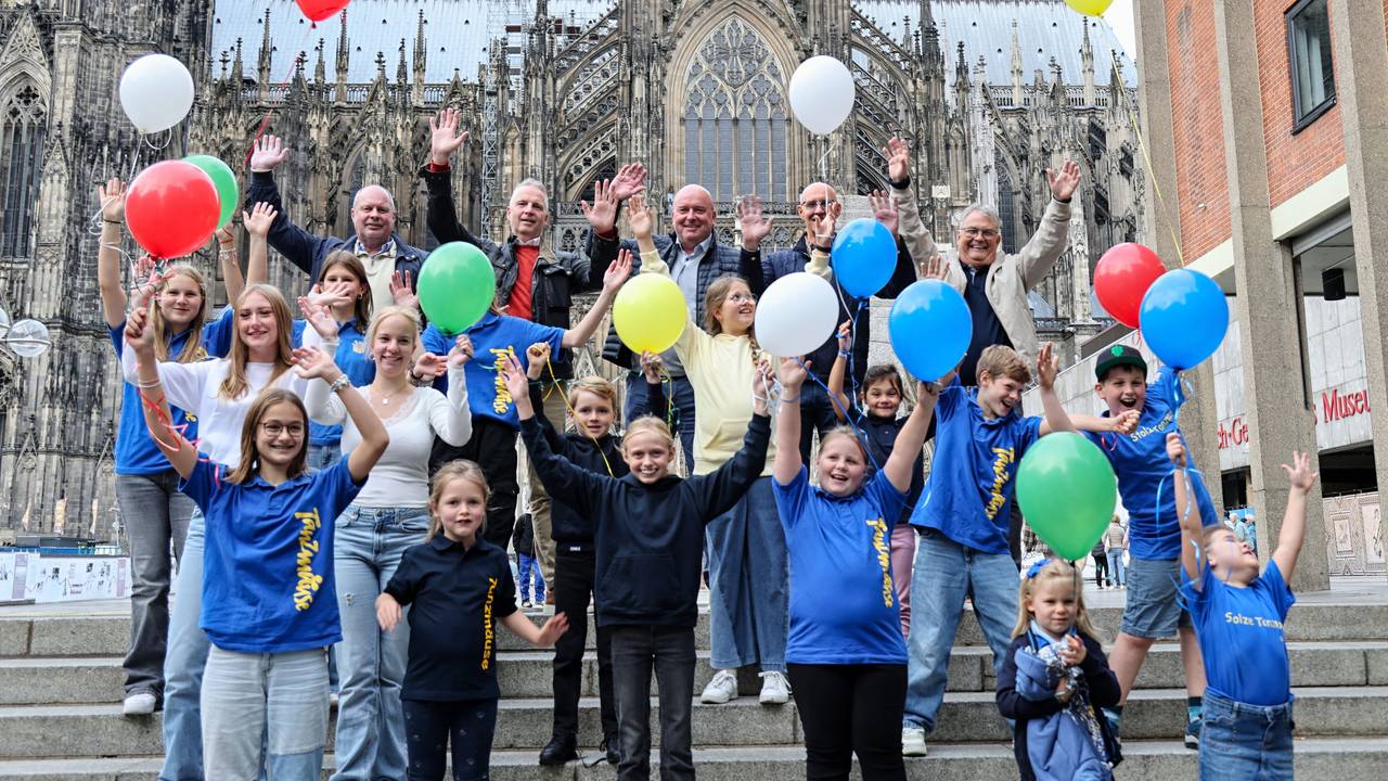 Kinder der Bürgergarde stehen mit bunten Luftballons vor dem Dom.