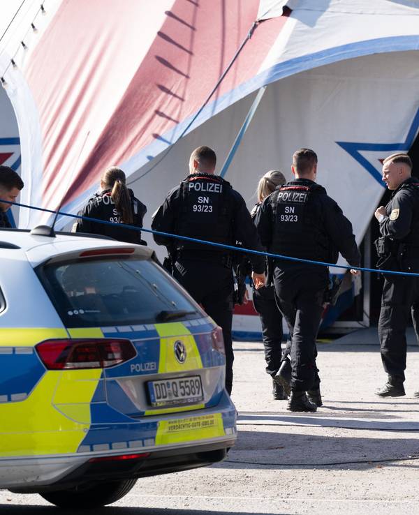 Polizisten und Polizistinnen gehen auf ein Zirkuszelt zu.