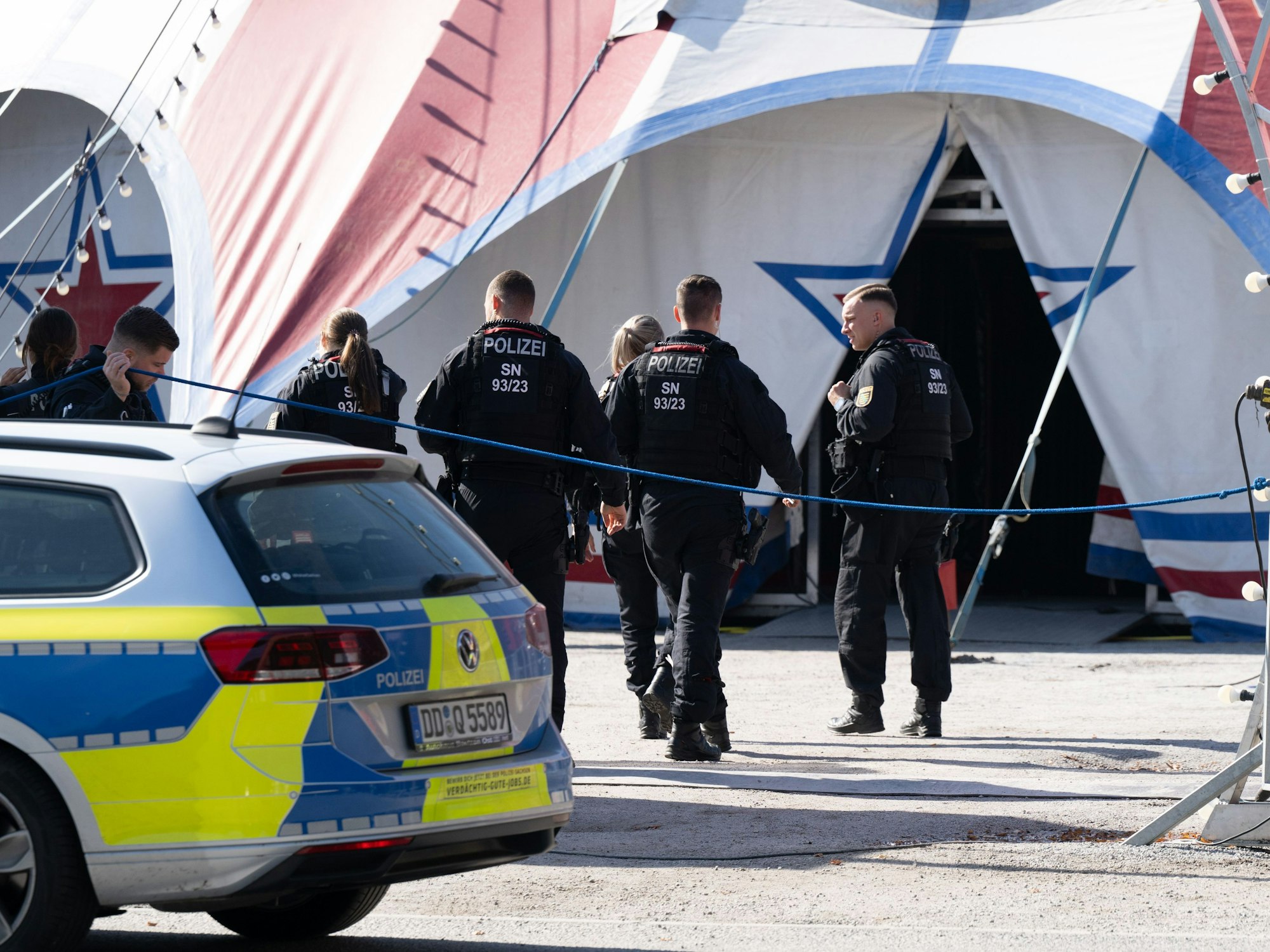 Polizisten und Polizistinnen gehen auf ein Zirkuszelt zu.