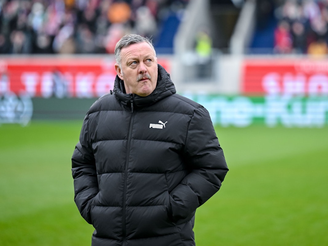 Roland Virkus steht mit verschränkten Armen auf dem Platz.