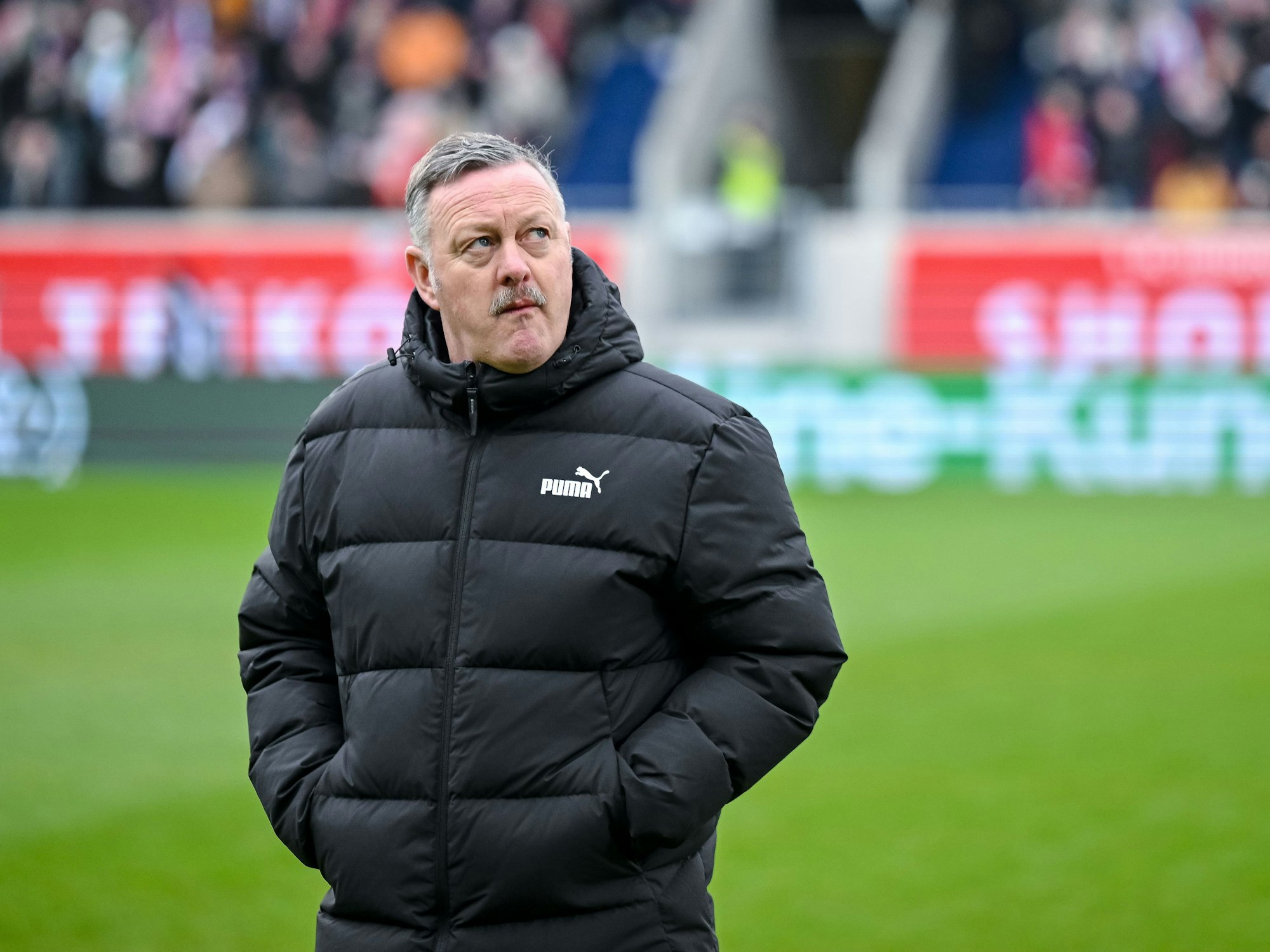 Roland Virkus steht mit verschränkten Armen auf dem Platz.