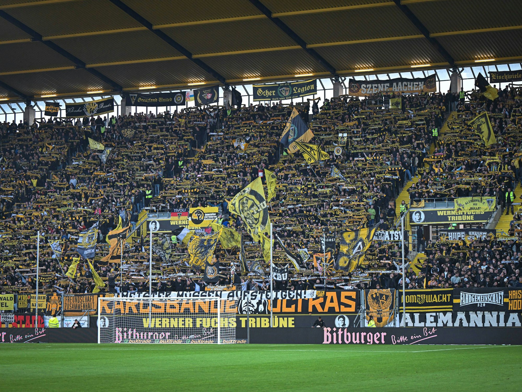Fans von Alemannia Aachen halten ihre Schals hoch.