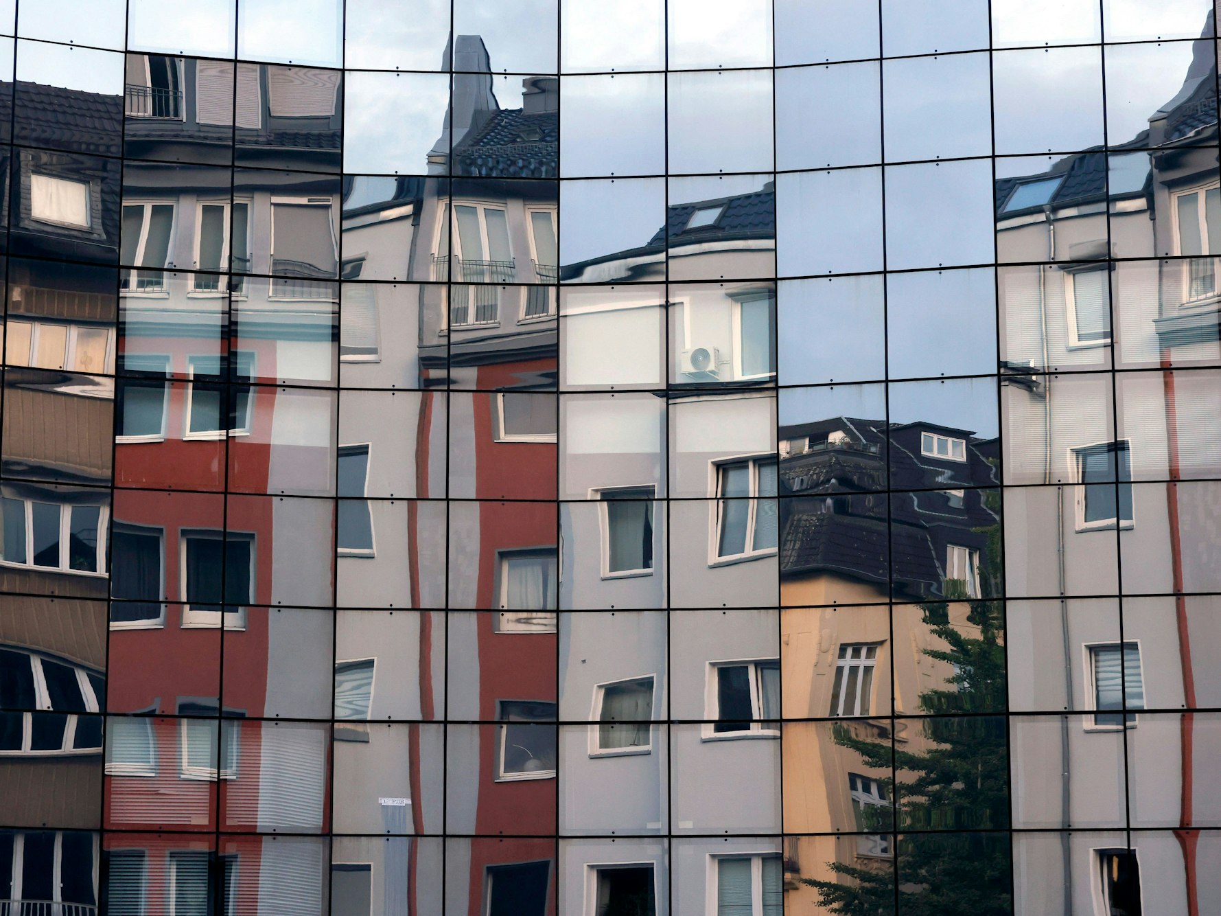 Häuser spiegeln sich in einer Fassade in der Kölner Innenstadt.: Wohnen wird in Köln nicht nur immer teurer, auch die Nachfrage nach Immobilien steigt.