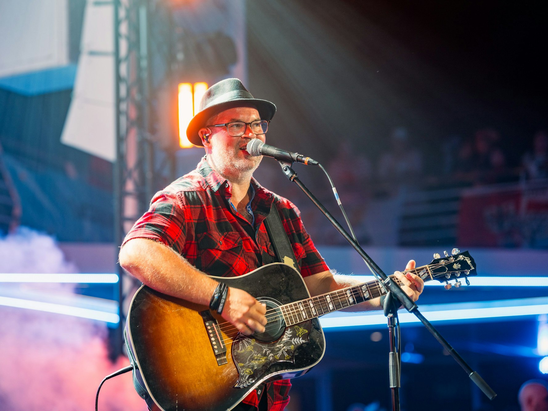 Björn Heuser steht mit Gitarre auf der Bühne.
