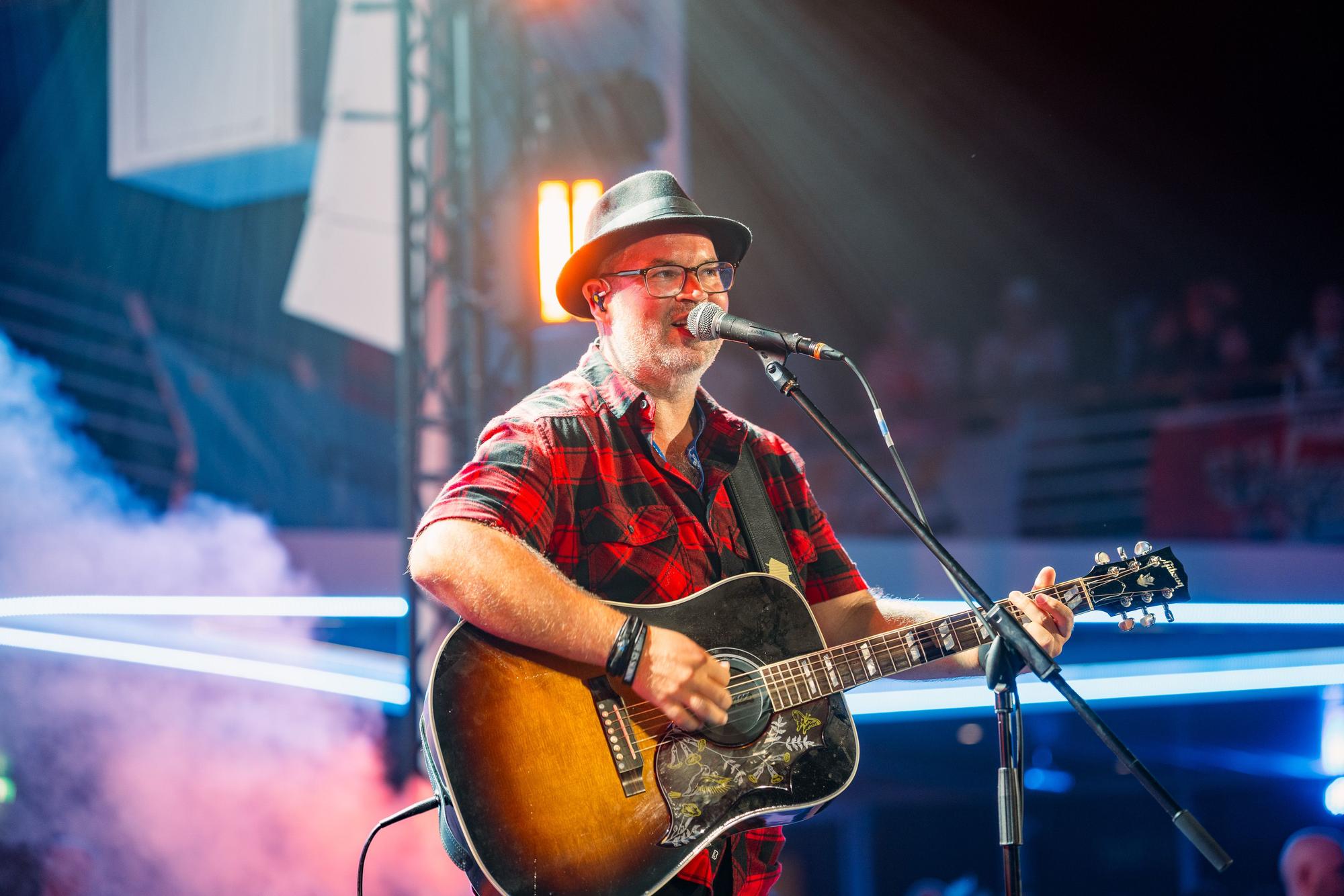 Björn Heuser steht mit Gitarre auf der Bühne.