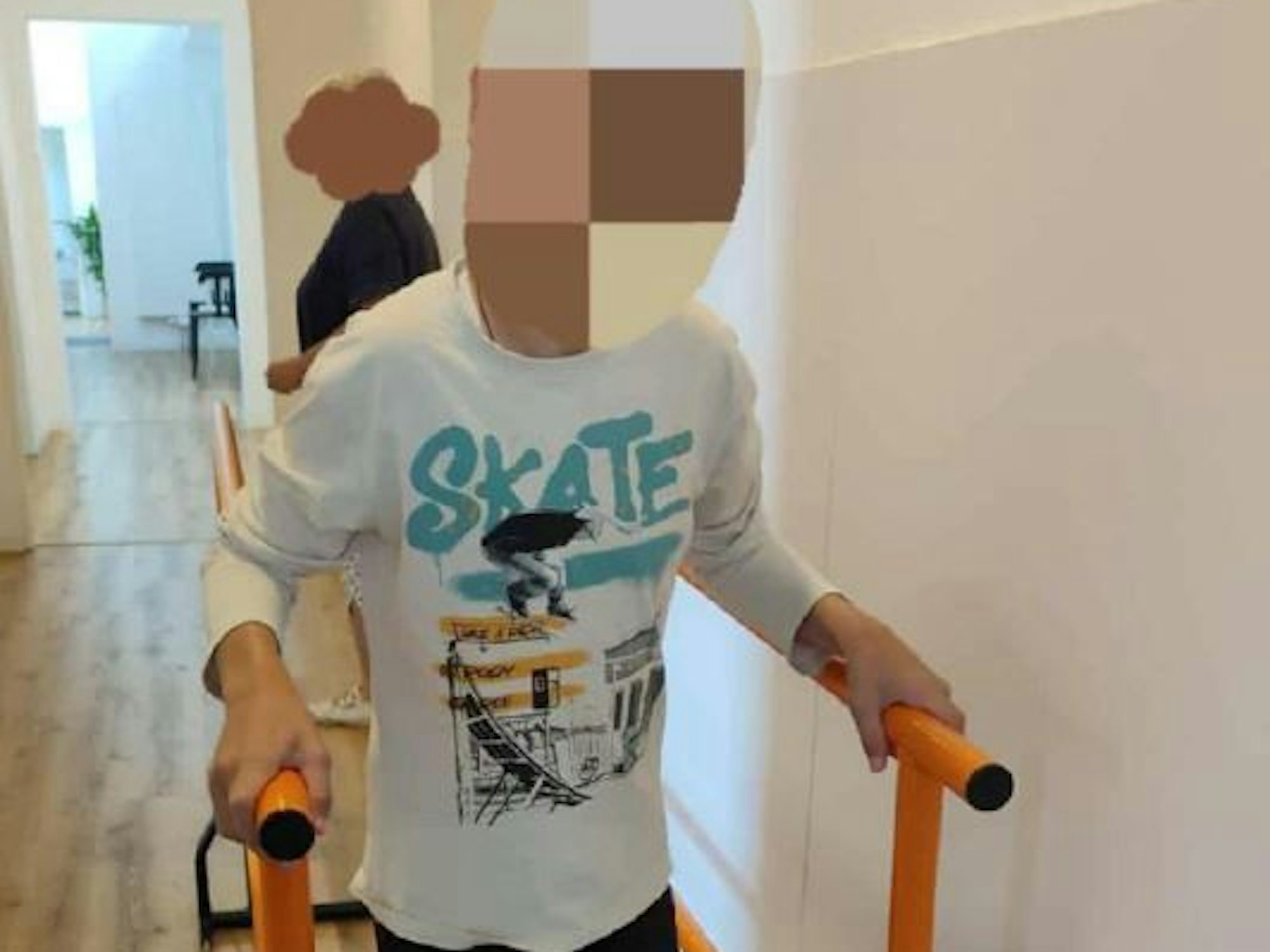 Ein Junge hält sich an zwei Stangen fest, damit er stehen kann.