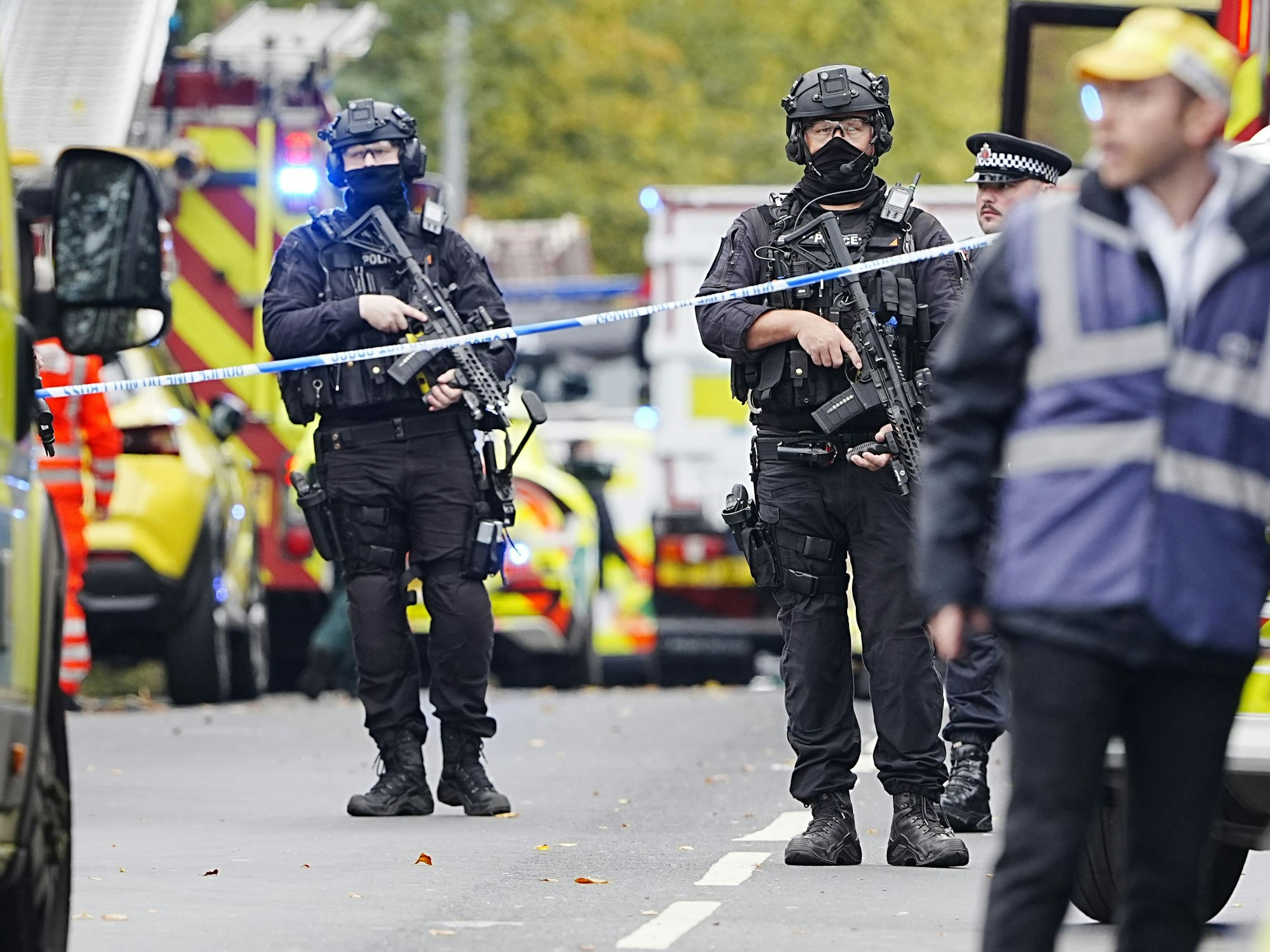Bewaffnete Polizeibeamte stehen hinter iner Absperrung.