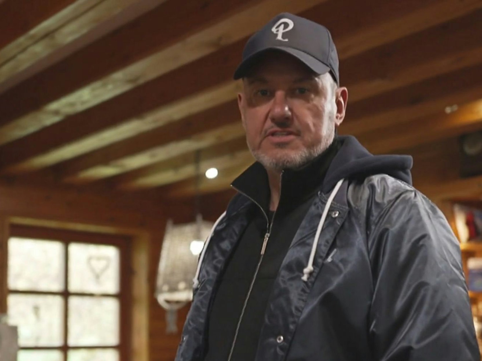 Der Gastrocoach Frank Rosin steht mit Basecap und Jacke in einem Raum.