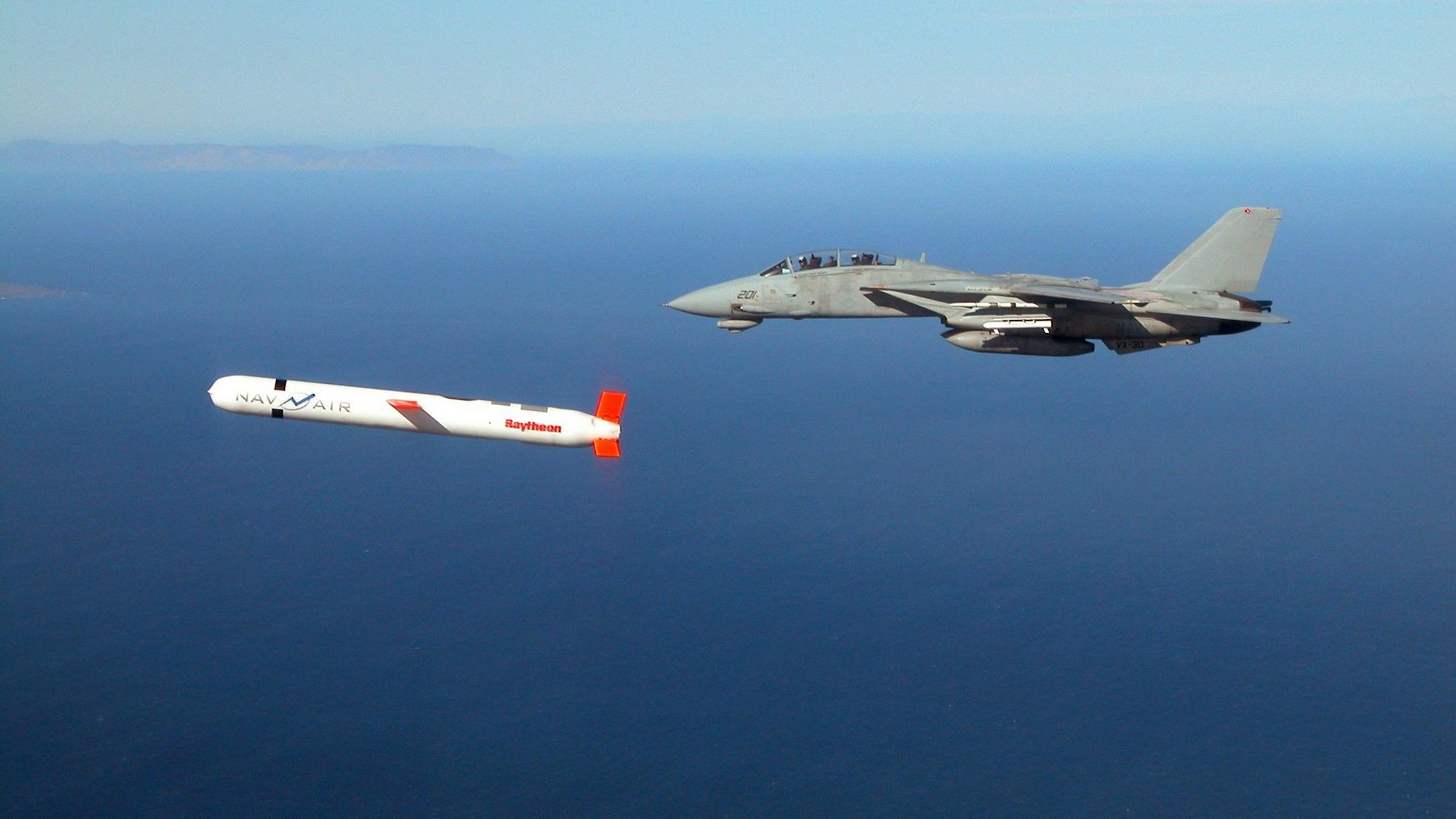 Neben einem Kampfjet fliegt eine Rakete.