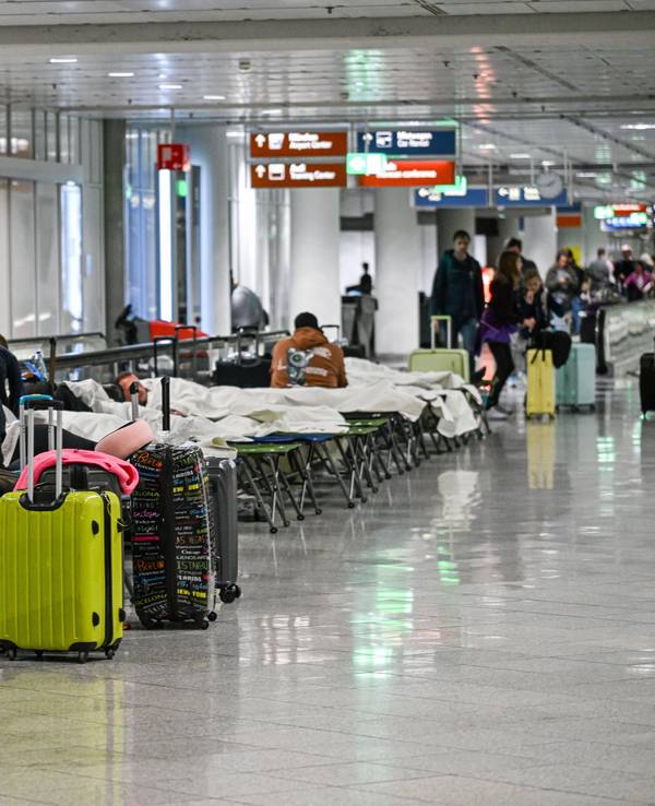 Menschen warten auf Feldbetten. Wegen einer Drohnensichtung sind am Flughafen in München am Donnerstagabend mehrere Flüge ausgefallen.