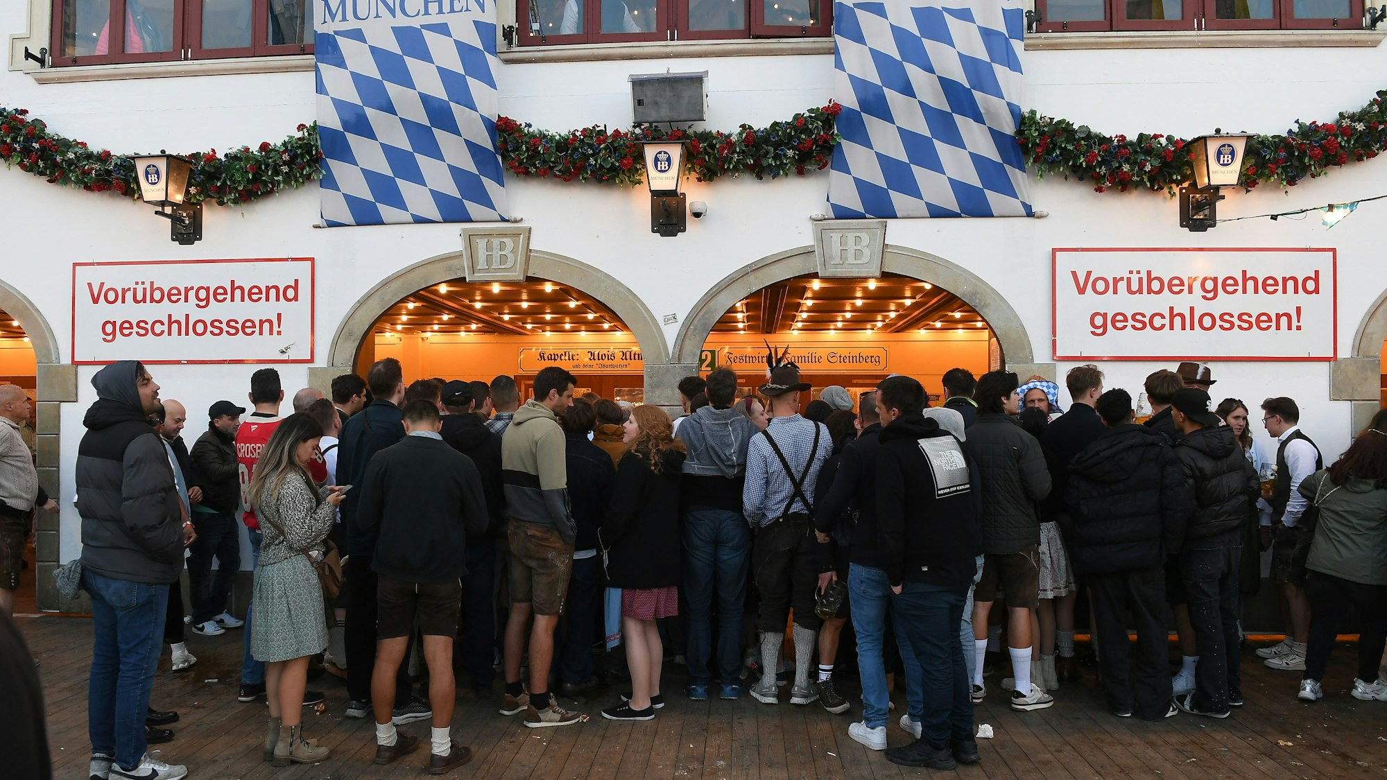 „Vorübergehend geschlossen“ steht am Eingang des Hofbräuzelt, vor dem zahlreiche Menschen stehen.