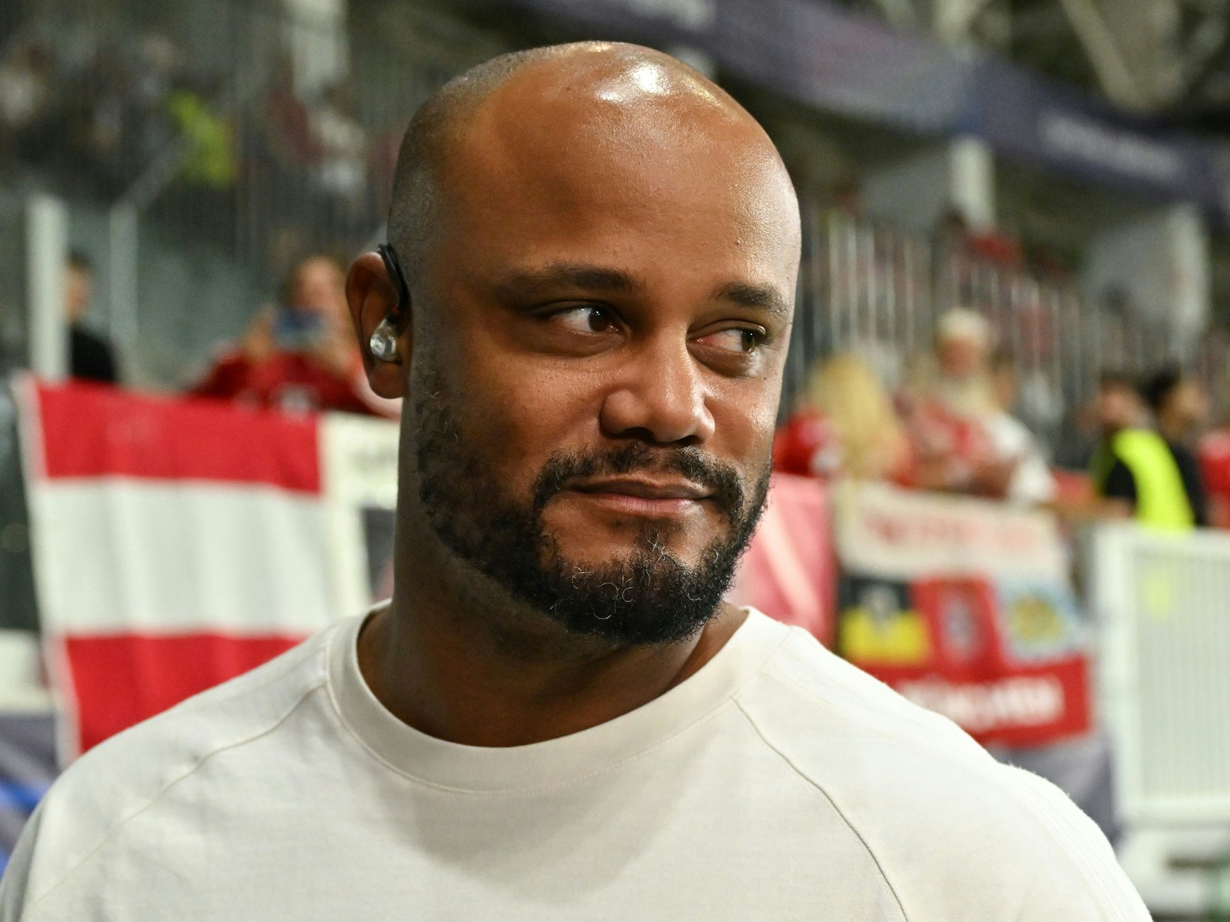 Bayern-Trainer Vincent Kompany trägt bei einem Interview Kopfhörer.
