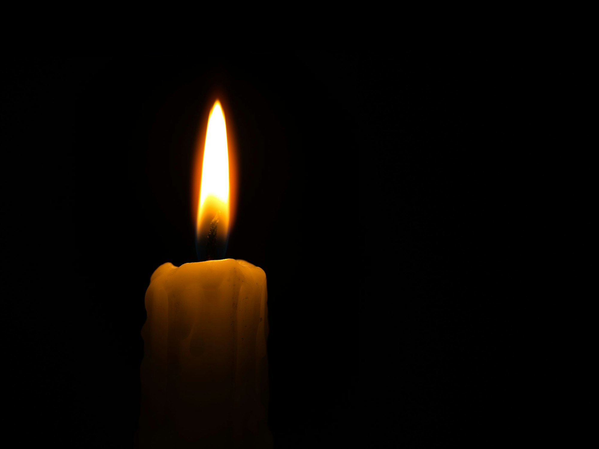Eine Kerze brennt in der Dunkelheit.