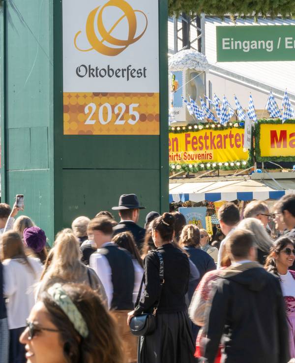 Wiesn-Besucherinnen und -besucher gehen durch den Haupteingang zum 190. Münchner Oktoberfest auf der Theresienwiese.