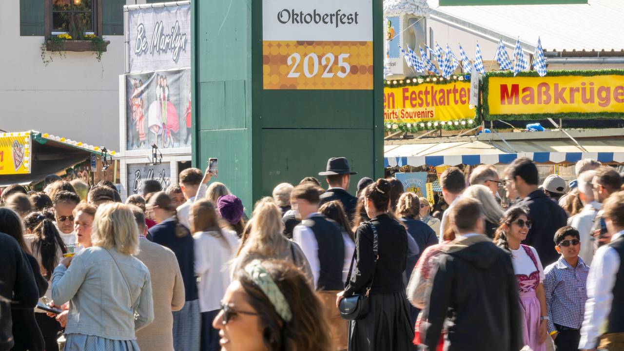 Wiesn-Besucherinnen und -besucher gehen durch den Haupteingang zum 190. Münchner Oktoberfest auf der Theresienwiese.