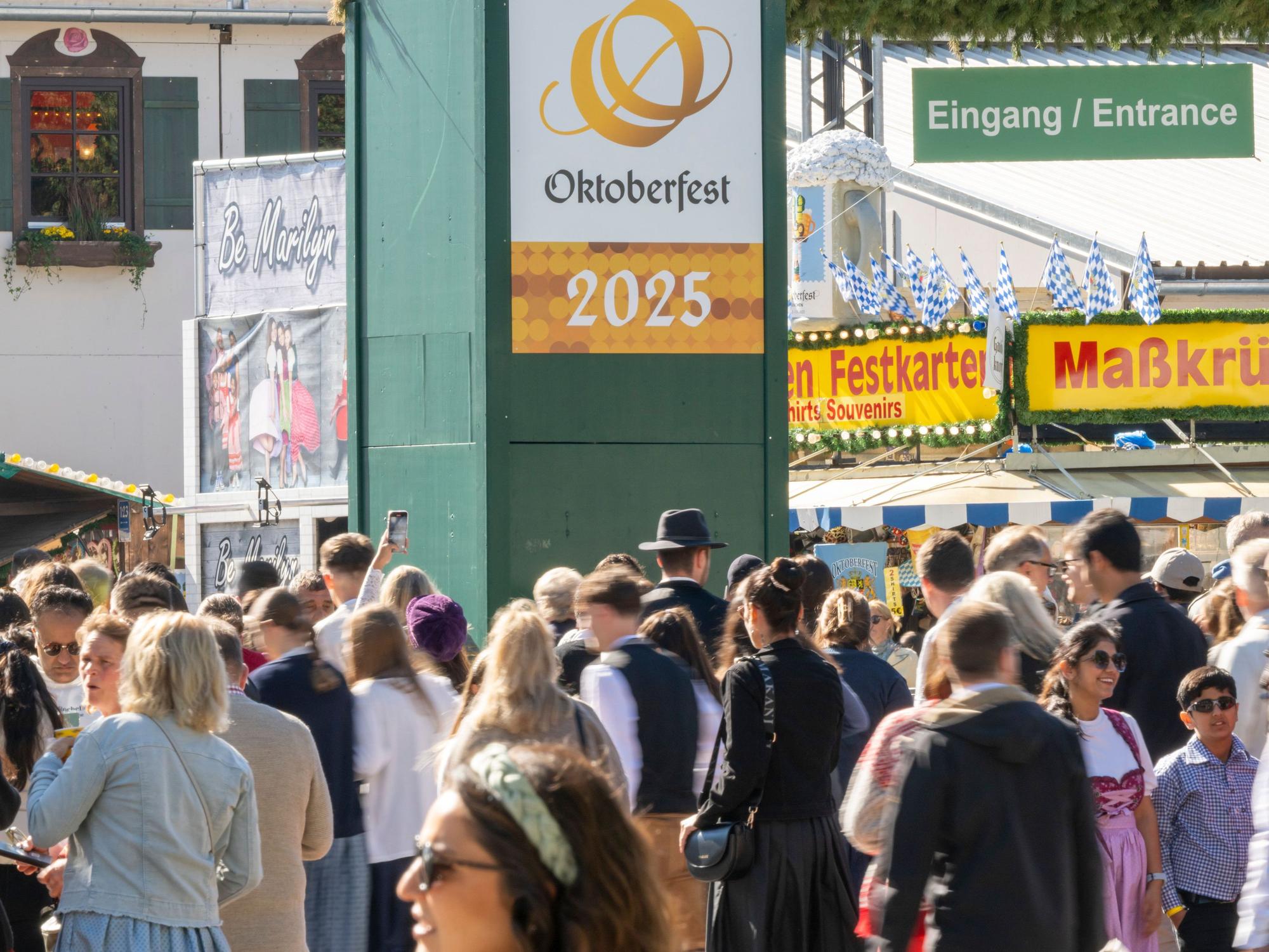 Wiesn-Besucherinnen und -besucher gehen durch den Haupteingang zum 190. Münchner Oktoberfest auf der Theresienwiese.