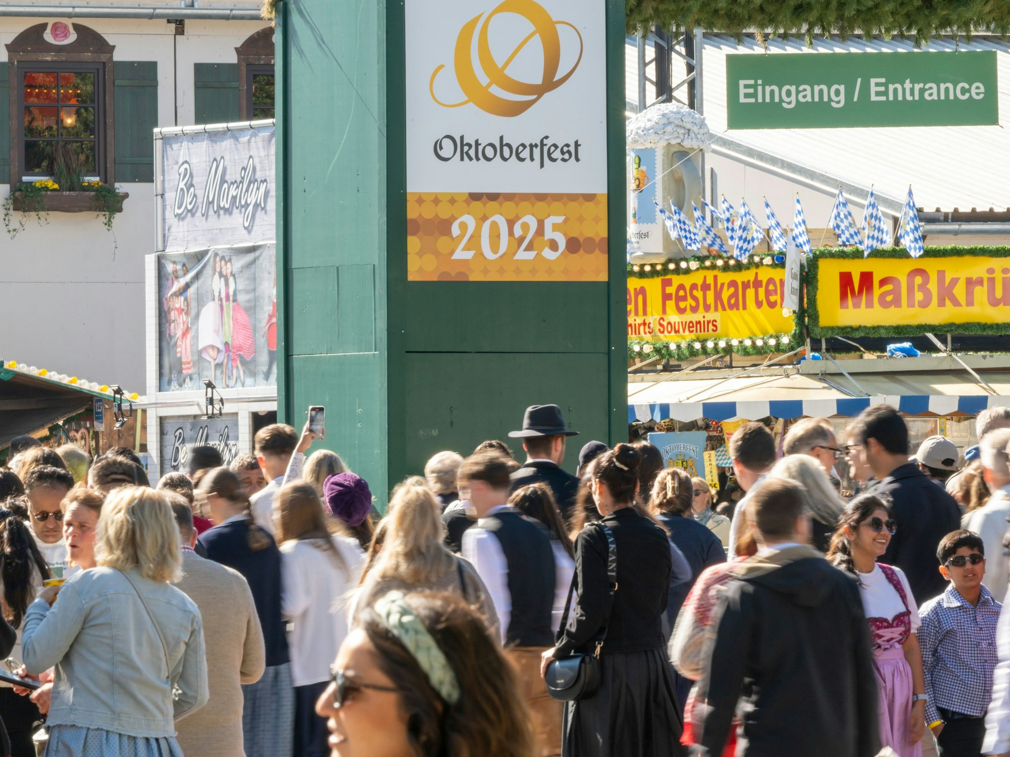 Wiesn-Besucherinnen und -besucher gehen durch den Haupteingang zum 190. Münchner Oktoberfest auf der Theresienwiese.