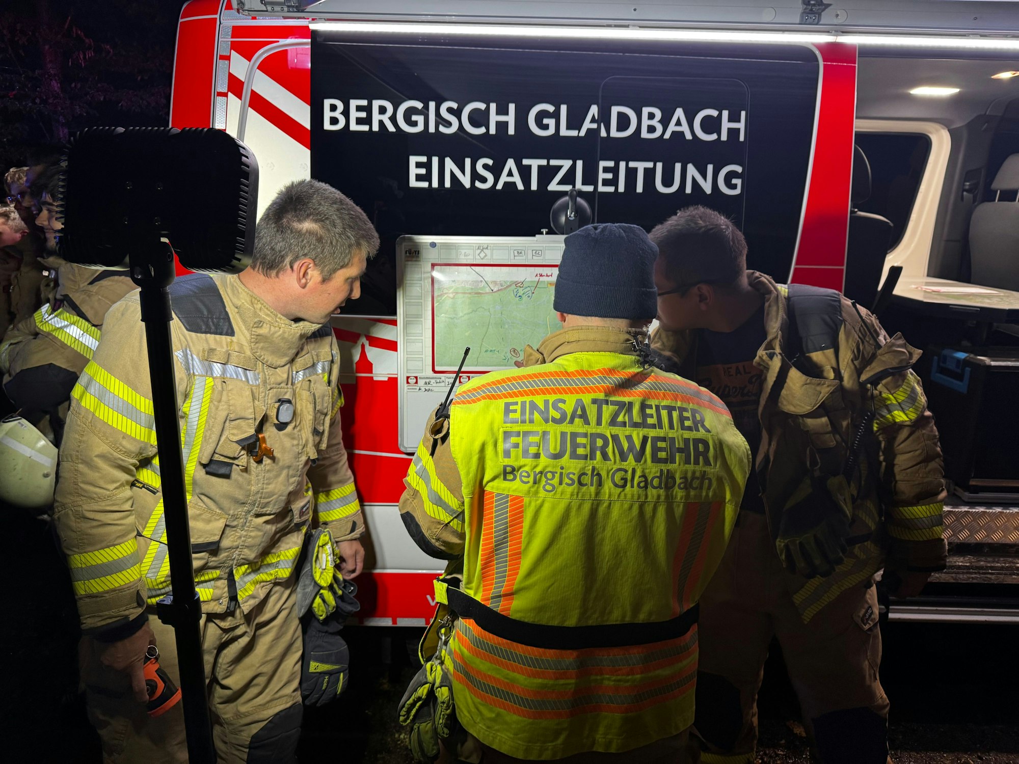 Drei Einsatzkräfte der Feuerwehr Bergisch Gladbach stehen zusammen und gucken auf eine Karte.