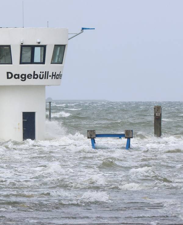 Wellen schlagen an einen Kontrollturm im Hafen. Teile des Fährhafens von Dagebüll werden bei einer Sturmflut überflutet.