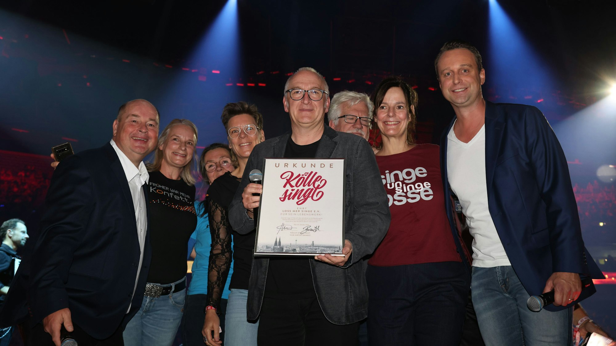 Das Team von „Loss mer singe“ steht mit Urkunde auf der Bühne.