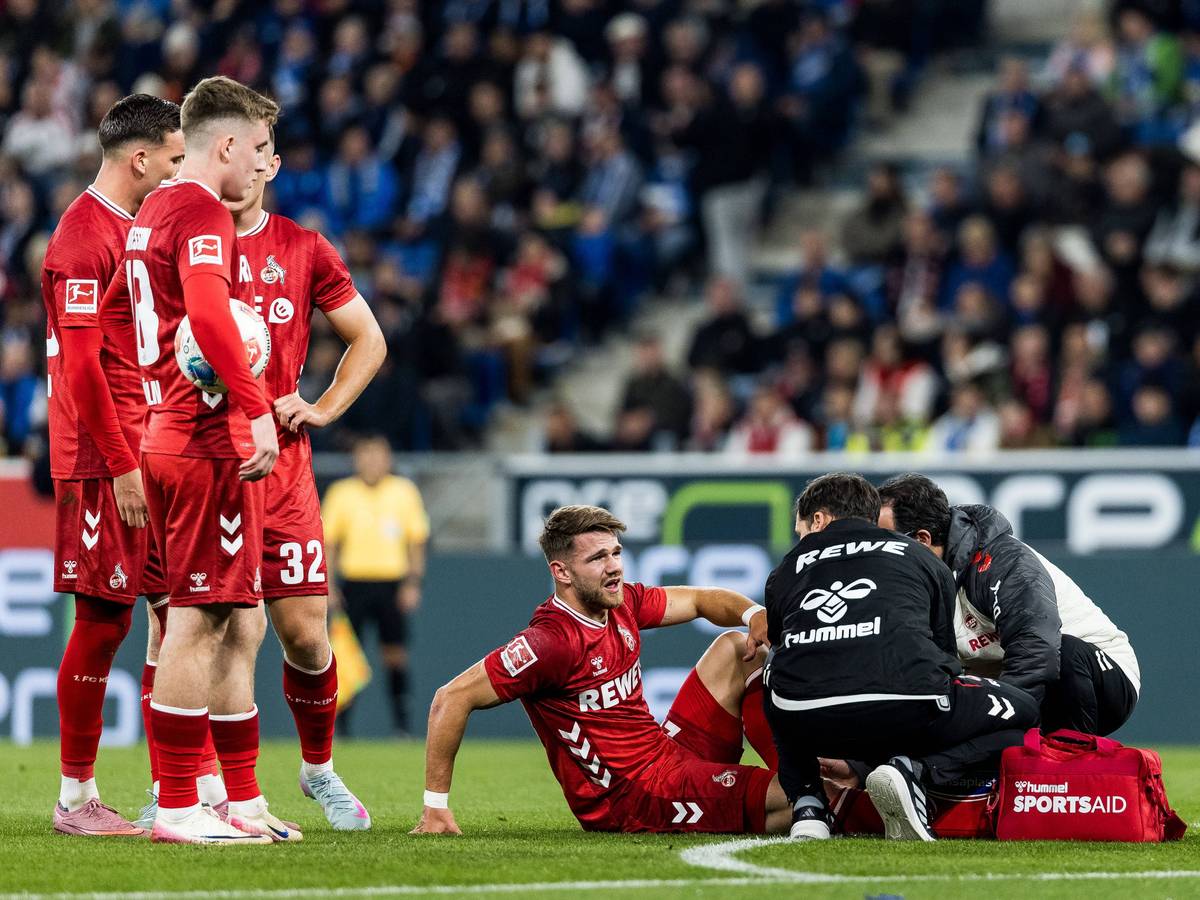 Jan Thielmann wird behandelt, seine FC-Kollegen stehen daneben und schauen zu.