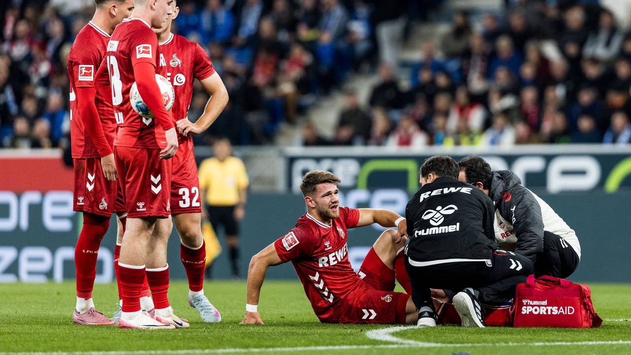 Jan Thielmann wird behandelt, seine FC-Kollegen stehen daneben und schauen zu.