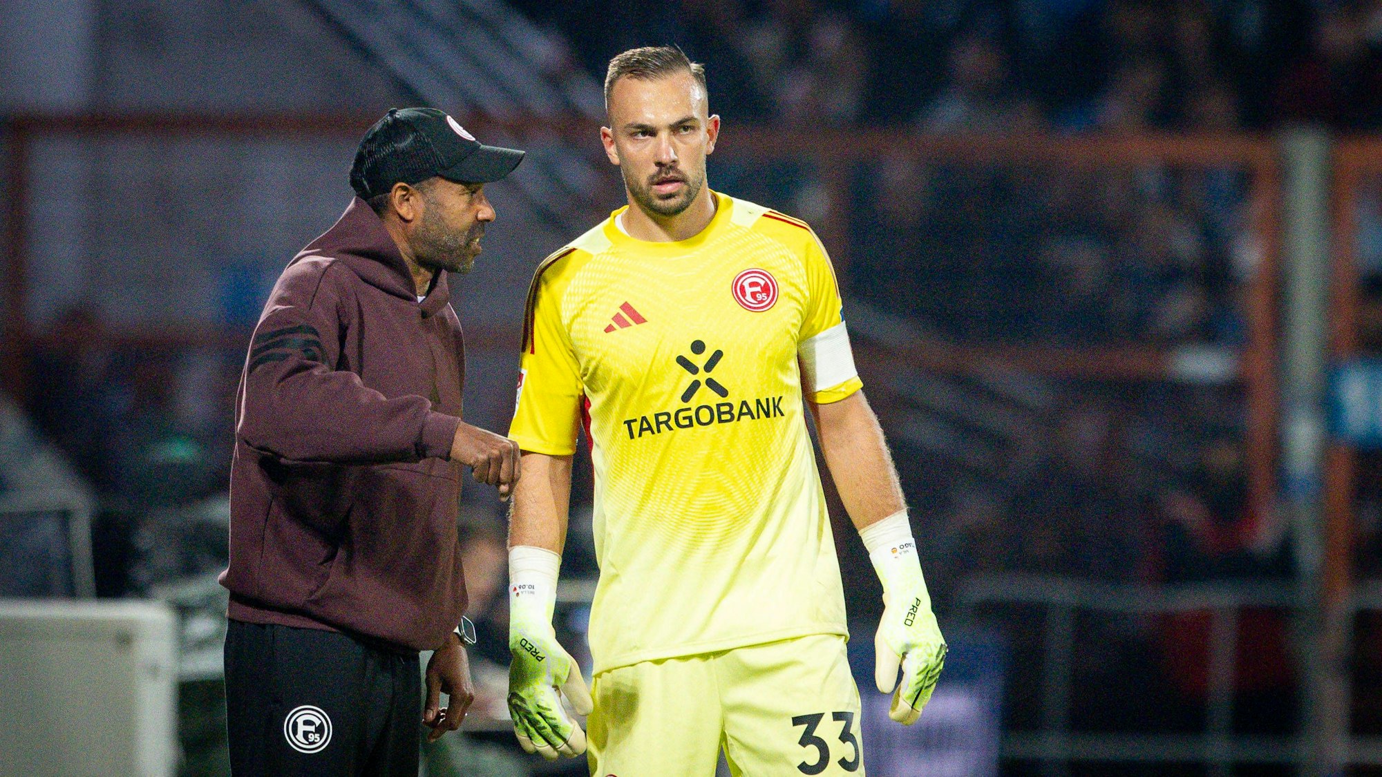 Daniel Thioune unterhält sich am Spielfeldrand mit Florian Kastenmeier (r.).
