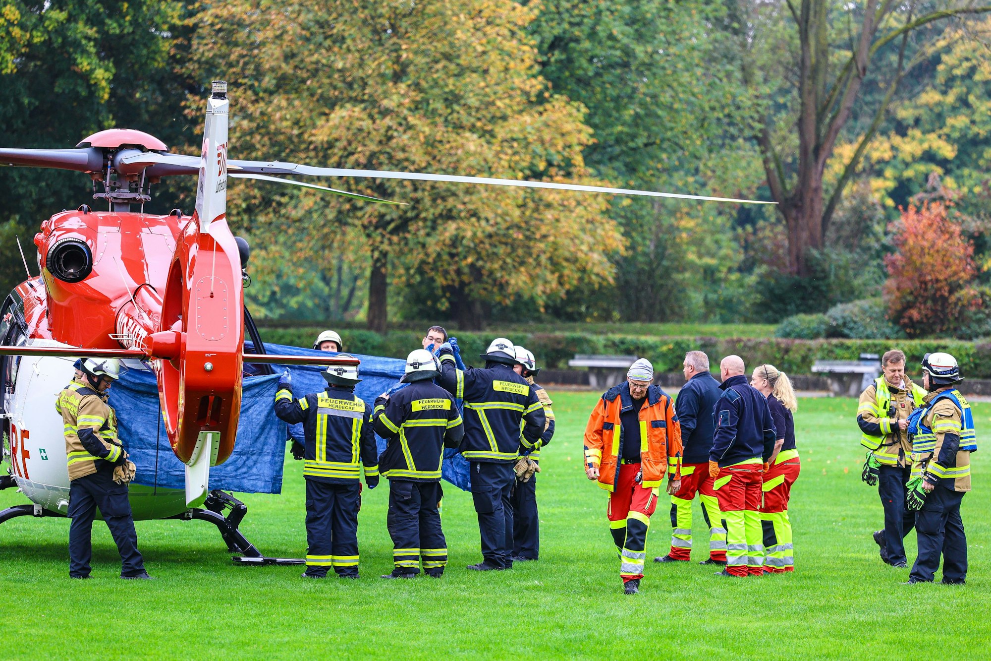 Einsatzkräfte stehen neben einem Rettungshubschrauber.