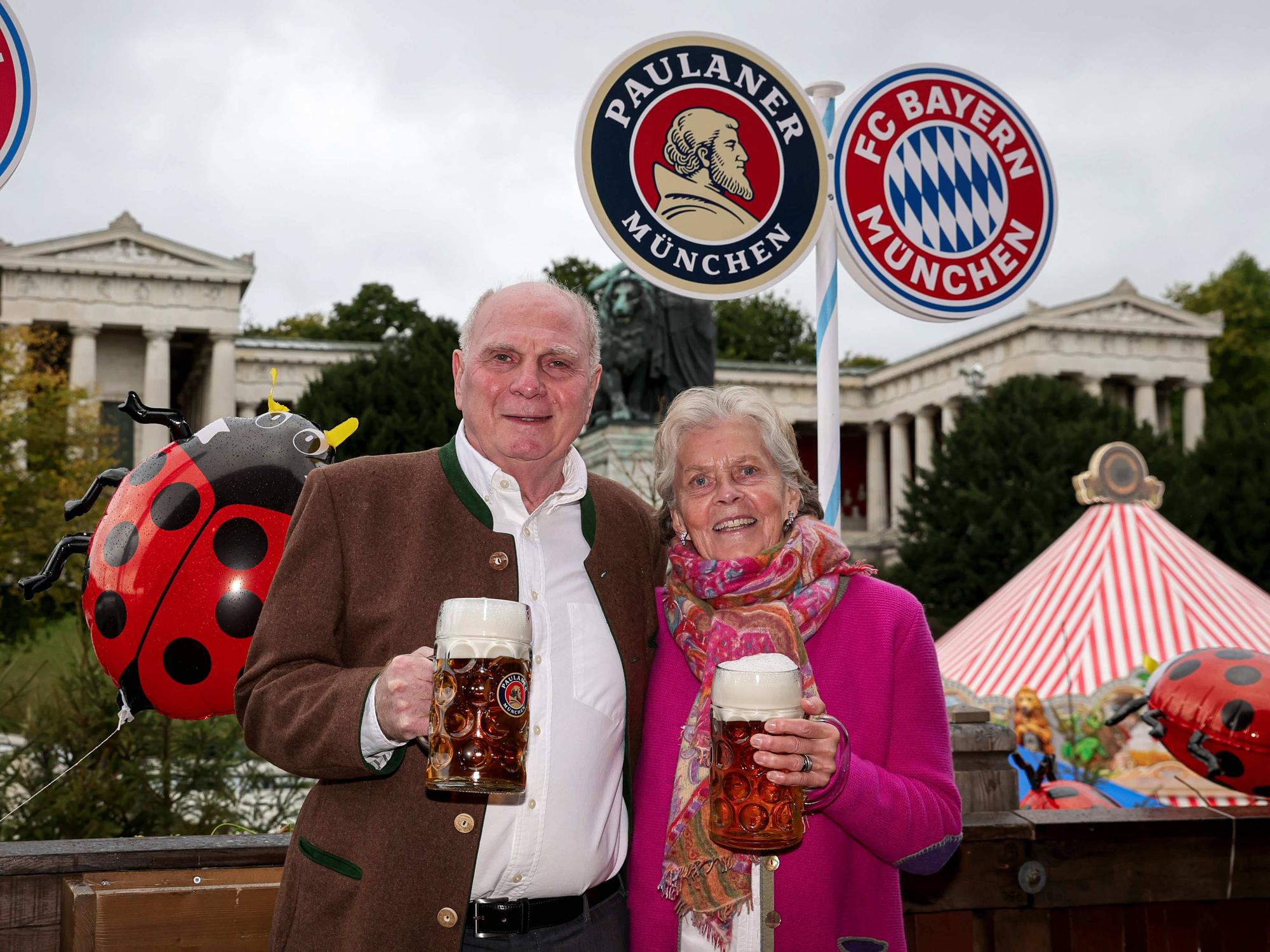 Uli Hoeneß und Sissy Hoeneß mit Bierkrügen vor Paulaner und Bayern Logos