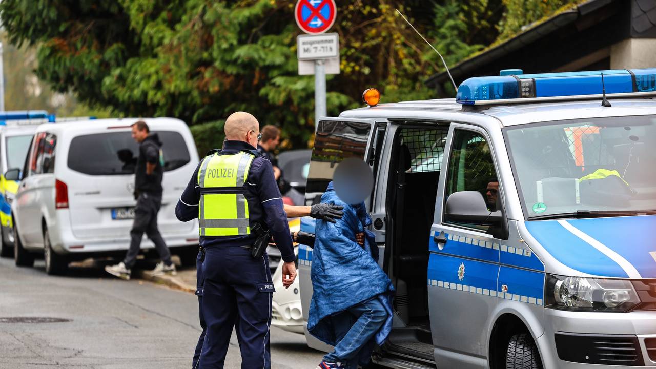 Polizisten bringen einen Jugendlichen zu einem Polizeiauto.