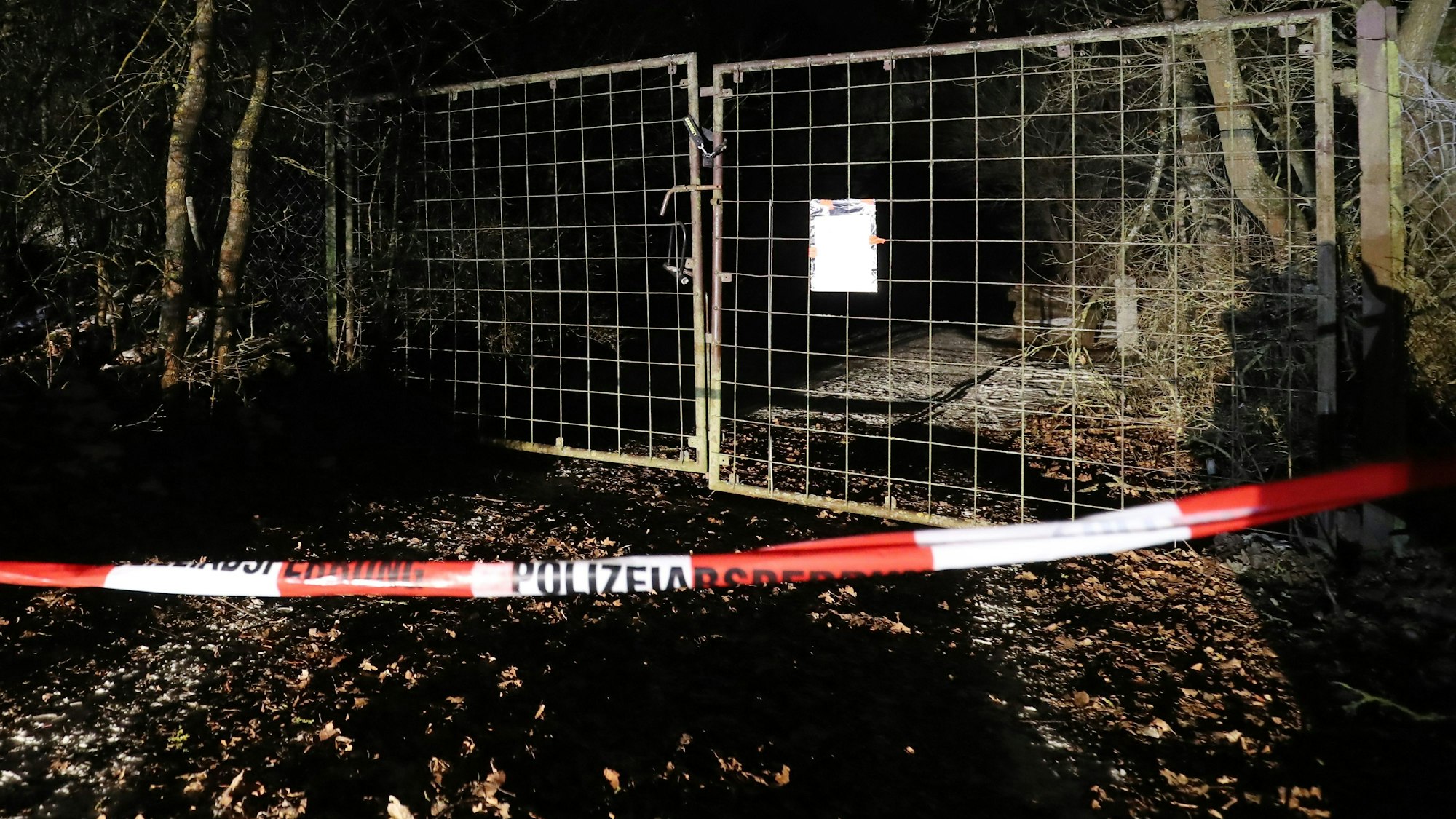 Die Polizei hat vor dem Tor einer Zufahrt zu einem Grundstück Flatterband gespannt.