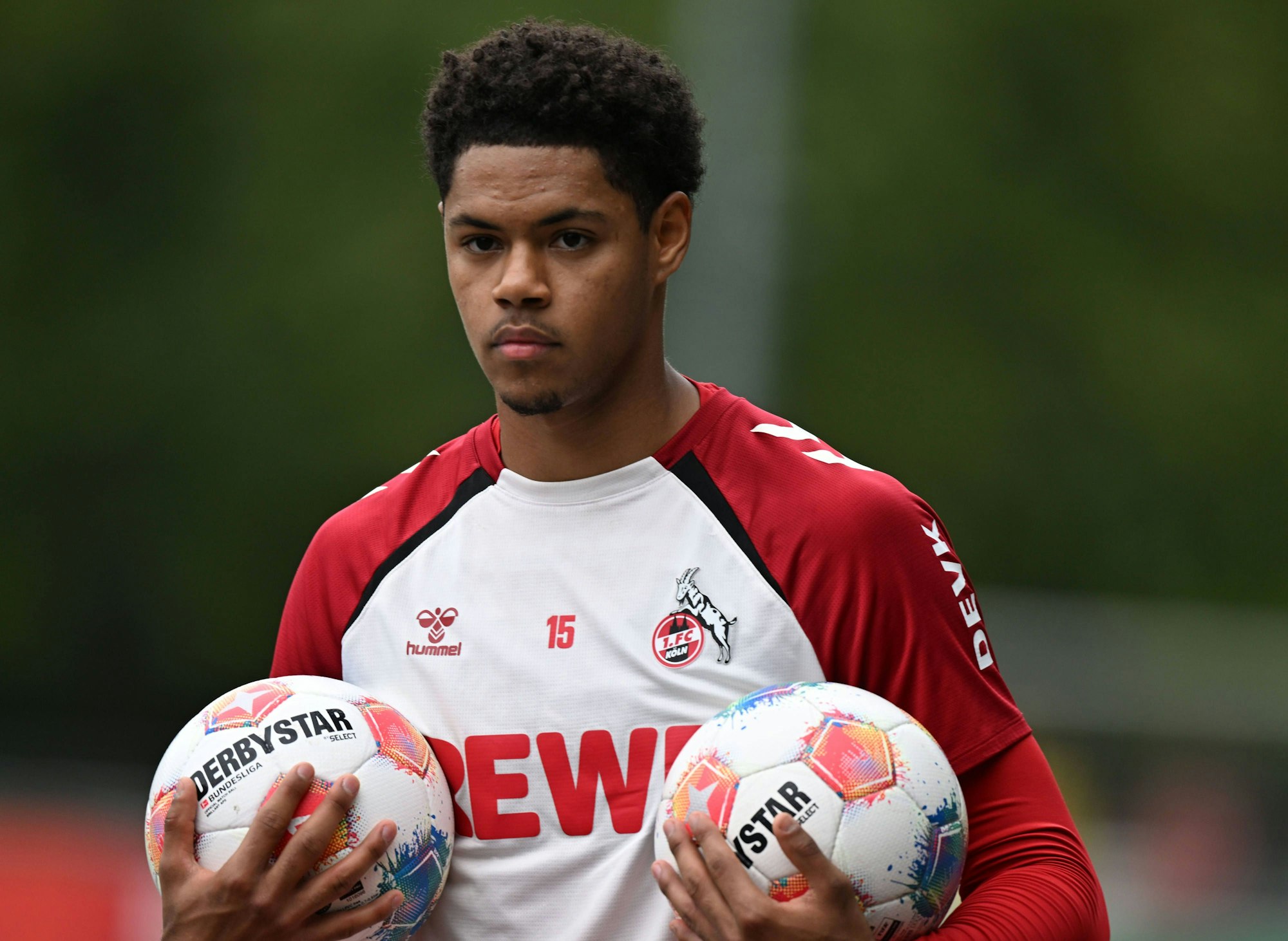 Yannick Mausehund trägt im FC-Training zwei Bälle.