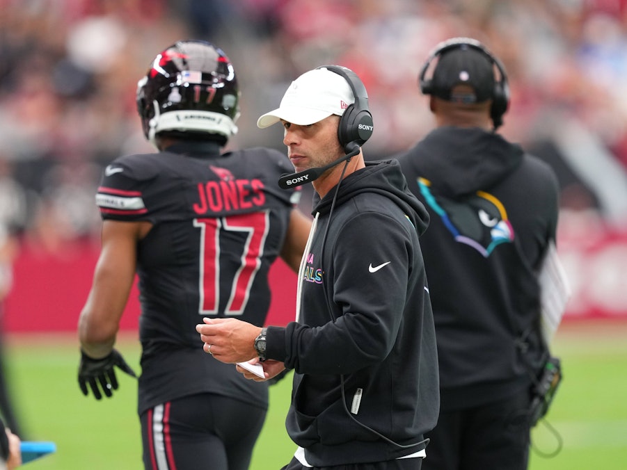 Jonathan Gannon als Trainer mit Headset und Notizen auf dem Footballfeld