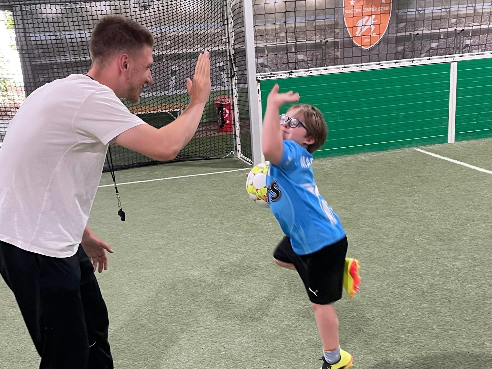 Tobias Gemein klatscht mit einem der jungen Kicker ab.
