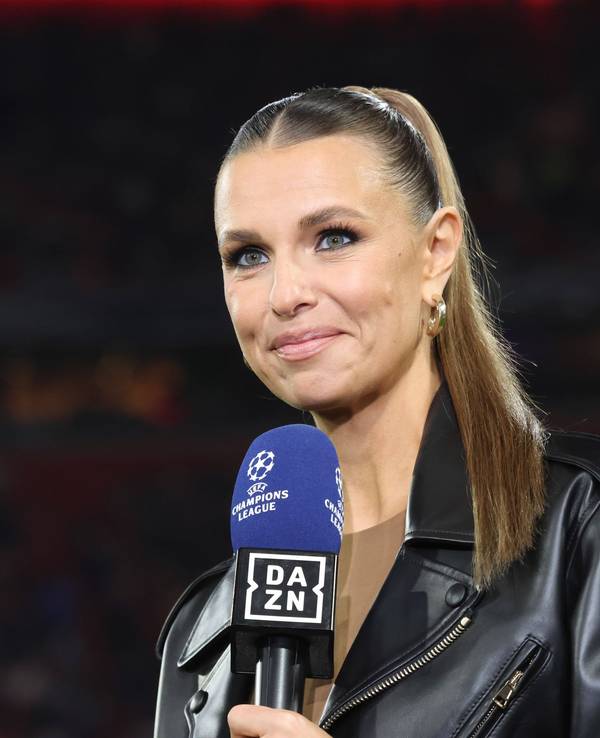 Laura Wontorra lächelt und hält ein DAZN Champions League Mikrofon