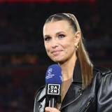 Laura Wontorra lächelt und hält ein DAZN Champions League Mikrofon