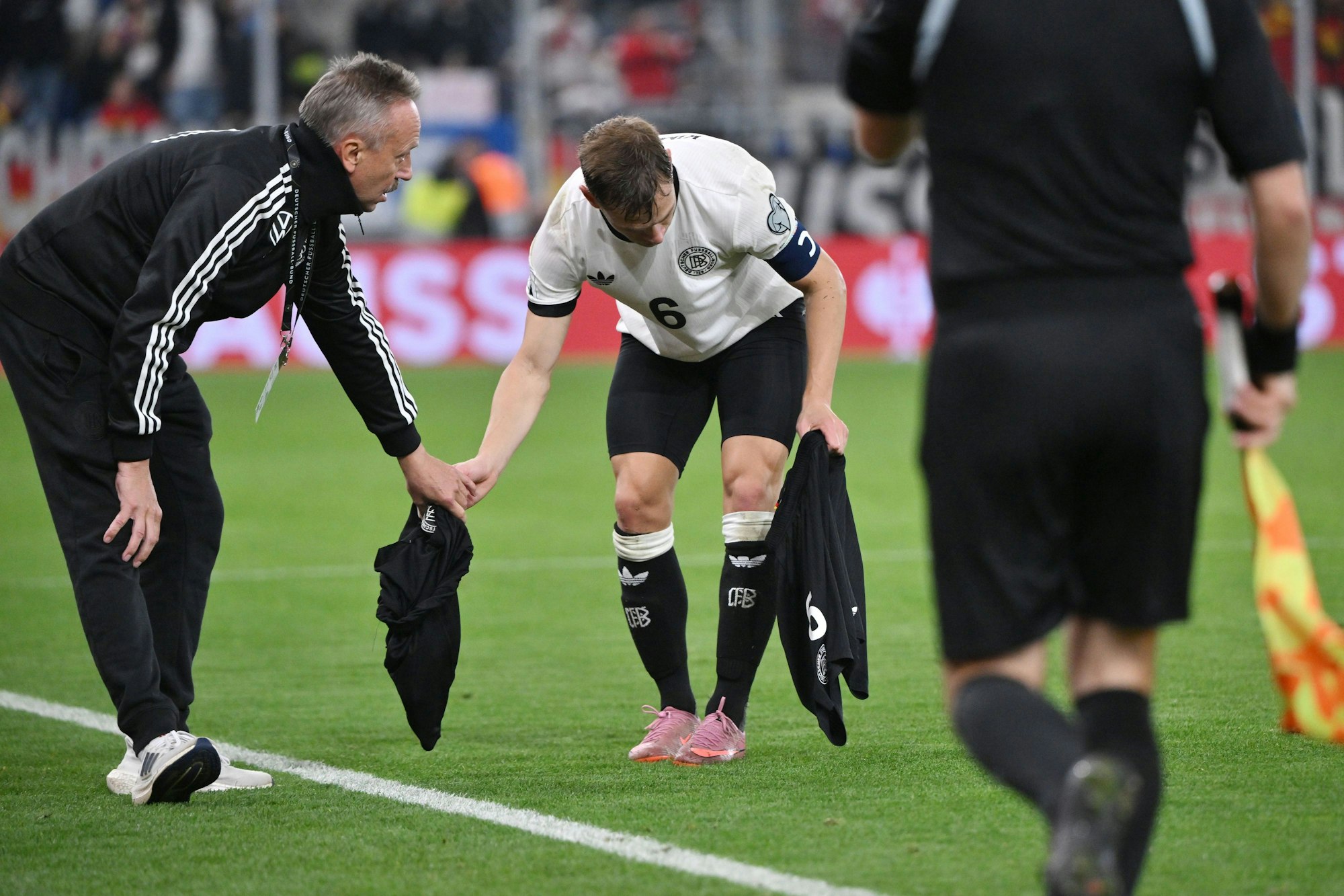 Joshua Kimmich wird eine neue Hose gereicht.