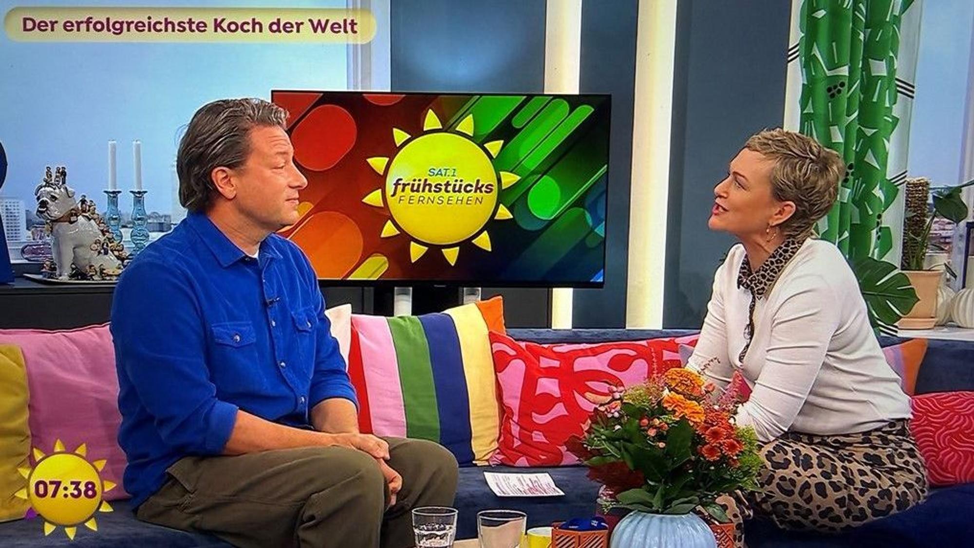 „Jamie Oliver“ Leuchtschild über hängenden grünen Lampen im Innenbereich