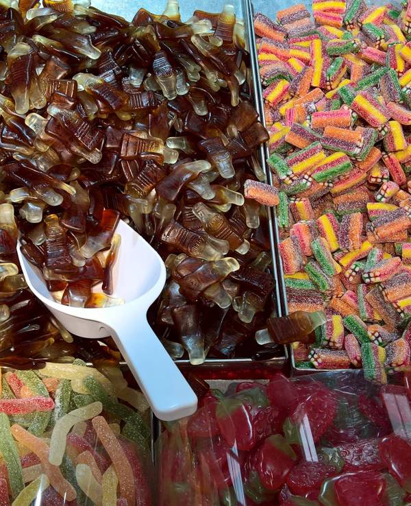 Bunter Süßigkeitenstand mit Gummibonbons, sauren Streifen und vielen braunen Colaflaschen-Gummis